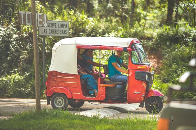 Mototaxi rojo en un camino rodeado de bosque