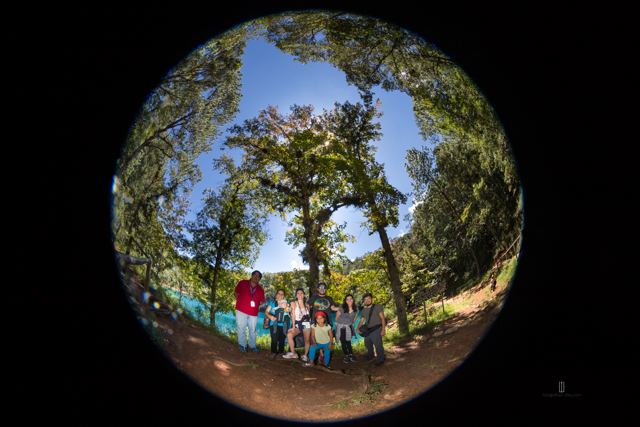Grupo de personas bajo los árboles junto a una laguna, con lente ojo de pez