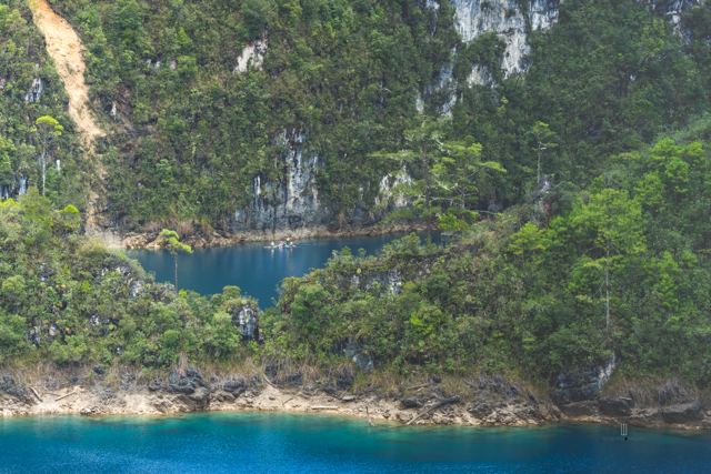 Laguna azul intenso al pie de paredes de roca con vegetación