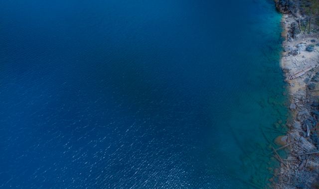 Agua azul profundo junto a una orilla rocosa, vista aérea