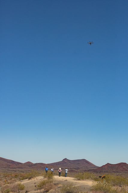 Dron volando sobre un grupo de personas en el desierto