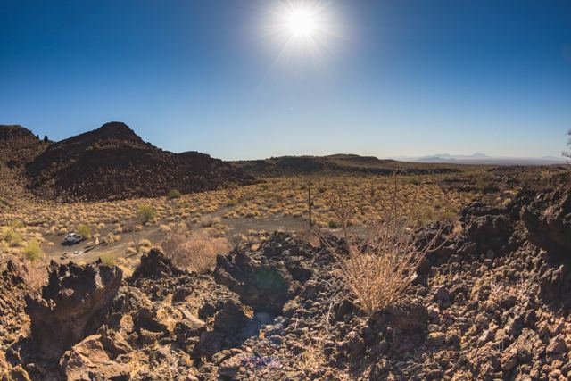 Roca volcánica oscura y matorrales bajo el sol