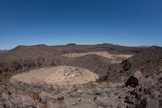 Hondonadas de arena clara entre roca volcánica oscura