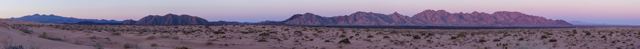 Panorámica del desierto y las montañas con luz rosada
