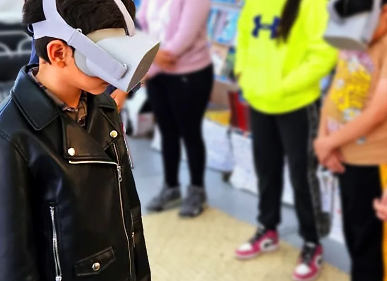 Niñas y niños con visores de realidad virtual en un estand de libros de la FILIJ