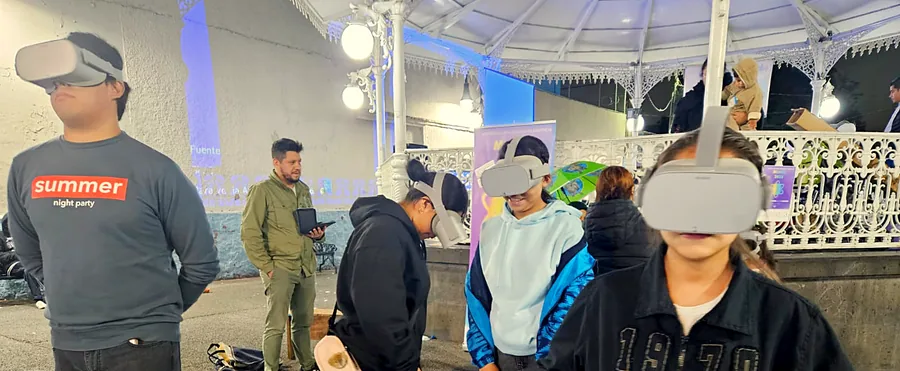 Jóvenes con visores de realidad virtual en una plaza, de noche